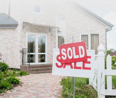 sold-sign-on-wooden-placard-with-sale-sign-in-front