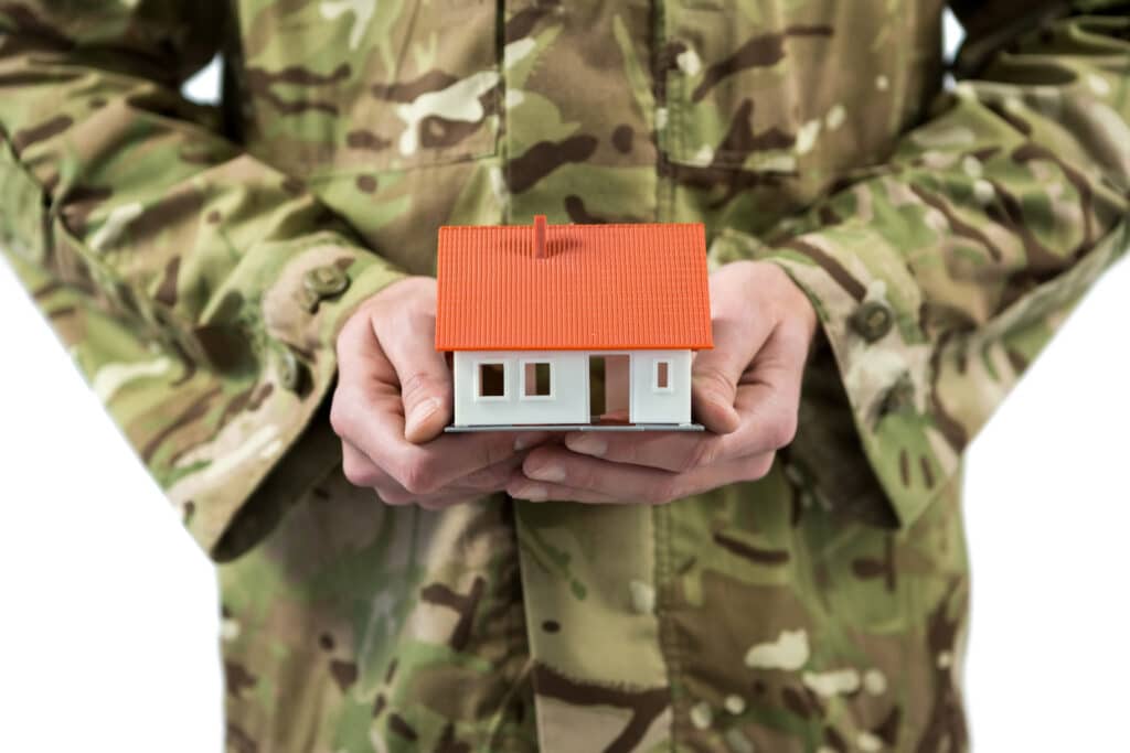 holding-a-miniature-house-wearing-camouflage-jacke-2026-01-11-10-31-05-utc