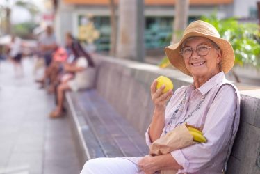 Cheerful senior attractive woman sitting outdoors in the city st