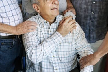 Elderly men cheer up his friend on a wheelchair