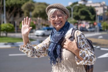 Happy senior woman traveler in sunny city centre expressing posi